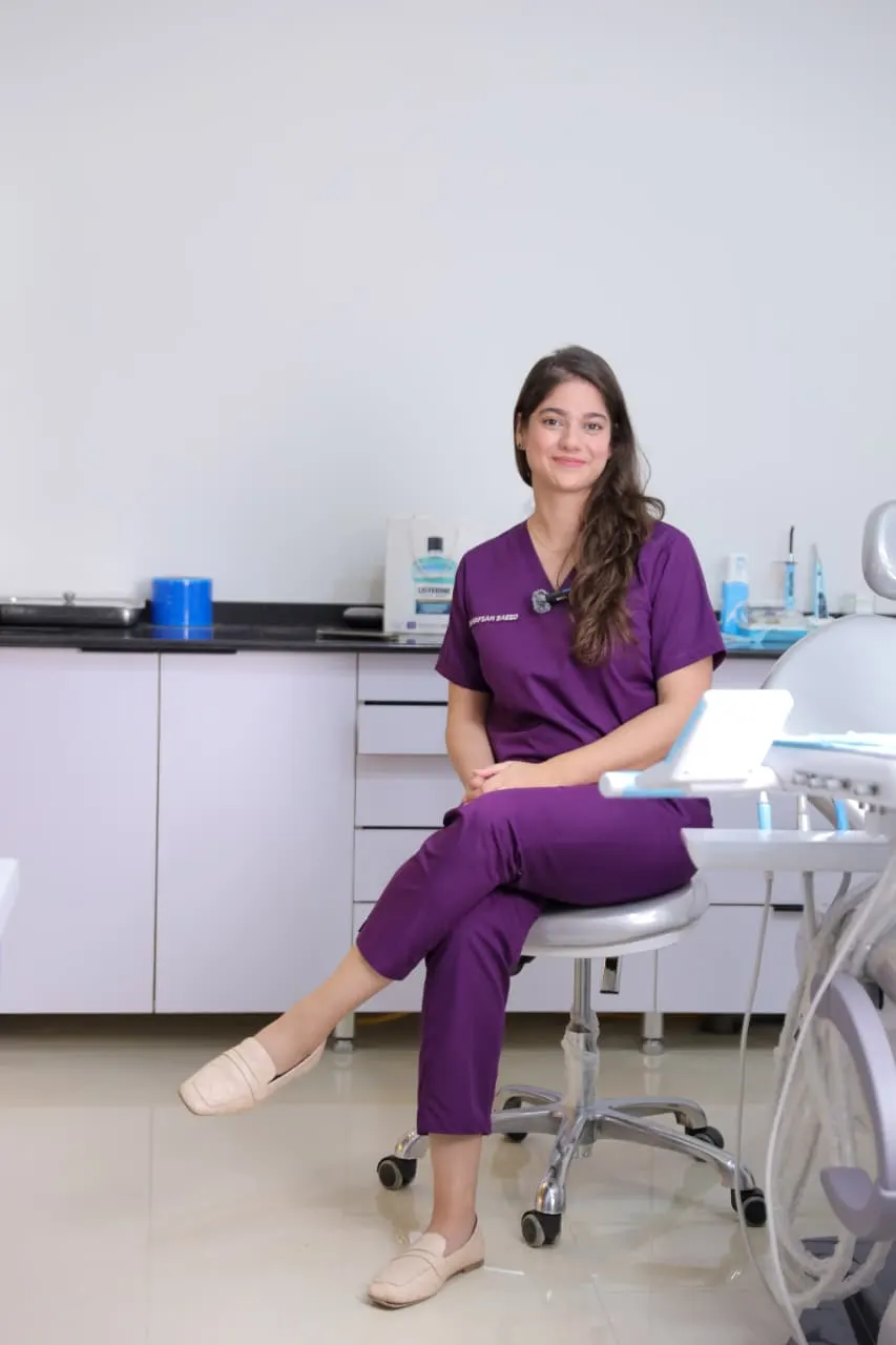 Dr. Hafsah Saeed, seated in purple scrubs in a treatment room.