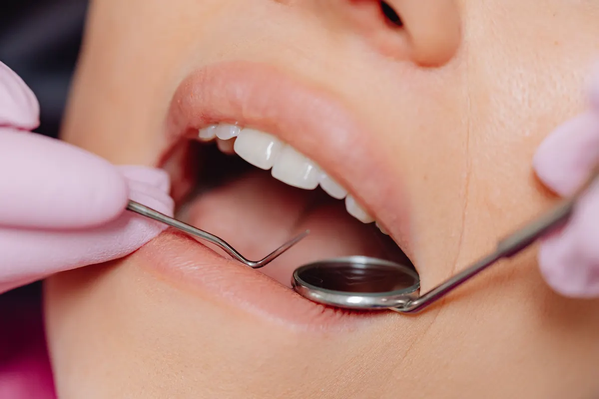 A dentist checking a patient's teeth with a mouth mirror and probe.