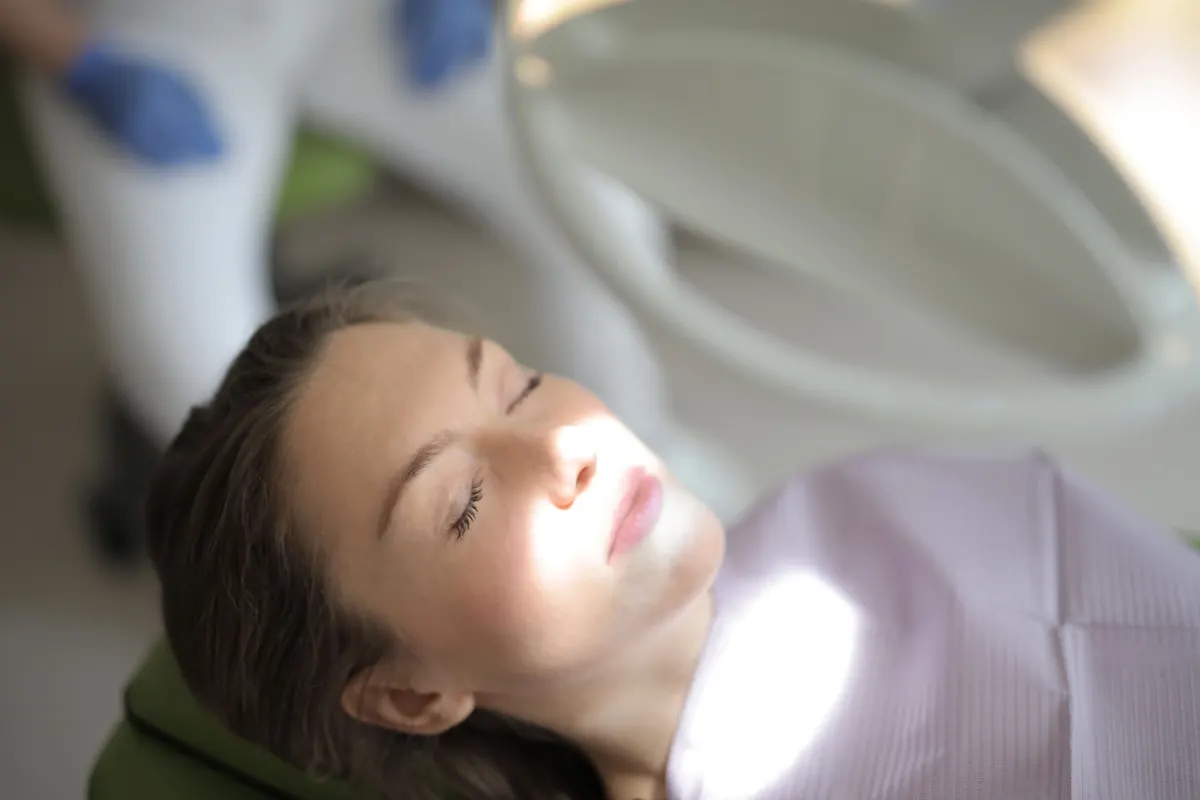 A relaxed patient resting in the dental chair with her eyes closed.